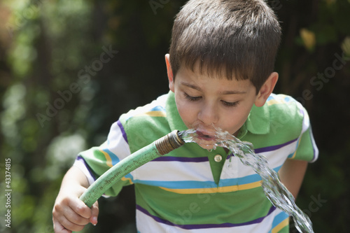 Photo: Caucasian boy drinking water from hose Caucasian boy drinking water from hose