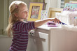 Caucasian girl dusting dresser