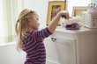 Caucasian girl dusting dresser