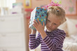 Caucasian girl listening to wrapped birthday gift
