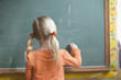 Photo : Caucasian girl solving math problem on blackboard Caucasian girl solving math problem on blackboard