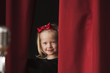 Caucasian girl peering from backstage
