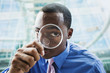 Black businessman using magnifying glass