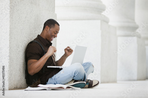 Photo: Black college student using laptop outdoors Black college student using laptop outdoors