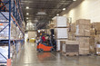 Worker driving forklift in warehouse