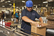 Hispanic worker packing boxes on assembly line