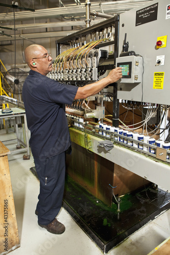 Photo: Hispanic worker operating factory control panel Hispanic worker operating factory control panel