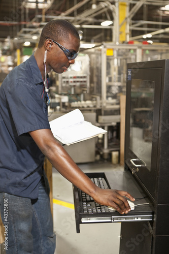 Photo: Black worker operating factory computer Black worker operating factory computer