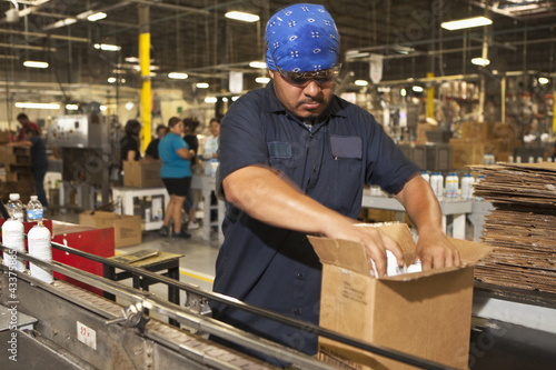 Photo: Hispanic worker packing boxes on assembly line Hispanic worker packing boxes on assembly line