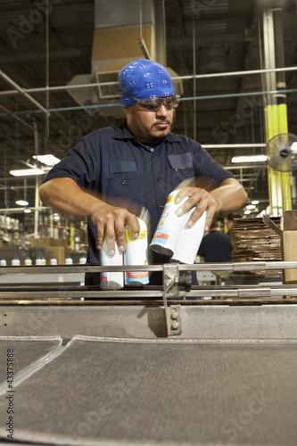 Photo: Hispanic worker holding cans on assembly line Hispanic worker holding cans on assembly line