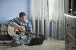 Mixed race boy holding guitar and using internet