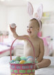 Caucasian baby girl in bunny costume with Easter eggs