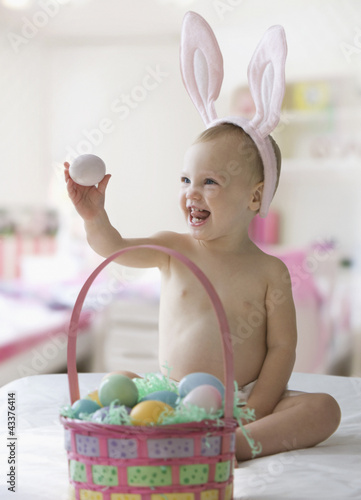 Photo: Caucasian baby girl in bunny costume with Easter eggs Caucasian baby girl in bunny costume with Easter eggs