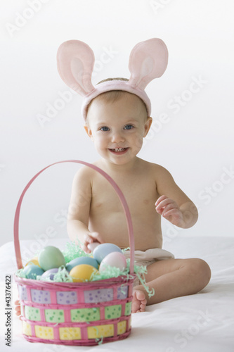 Photo: Caucasian baby girl in bunny costume with Easter eggs Caucasian baby girl in bunny costume with Easter eggs
