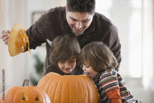 Photo: Mixed race father and sons carving Halloween pumpkins Mixed race father and sons carving Halloween pumpkins