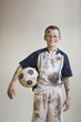 Dirty Caucasian boy holding soccer ball