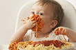 Mixed race baby boy eating spaghetti