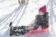 Hispanic girl sledding down snow covered hill