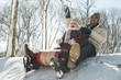 Father and daughter sledding down snow covered hill