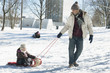 Father pulling daughter on sled