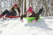 Hispanic girls sledding on snow covered hill