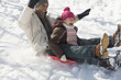 Father and daughter sledding on snow covered hill