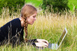 Junge Frau mit Laptop auf der Wiese