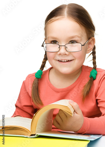 Foto: Cute cheerful little girl reading book Cute cheerful little girl reading book