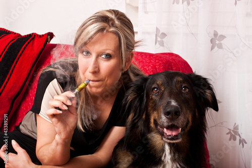 Photo: Blonde Frau mit Hund und elektrischer Zigarette Blonde Frau mit Hund und elektrischer Zigarette