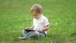 Baby boy working with Tablet PC sitting on the grass