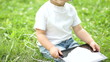 Video: Cheerful child with a Tablet PC sitting on the grass Cheerful child with a Tablet PC sitting on the grass