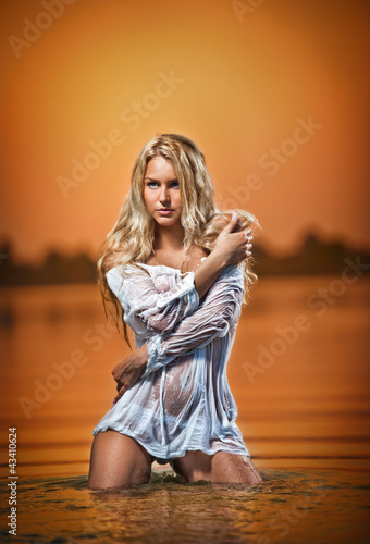 Photo: sexy blonde woman in water at sunset .Beautiful swimsuit model sexy blonde woman in water at sunset .Beautiful swimsuit model
