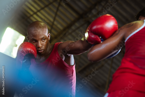 Photo: Two male athletes fight in boxing ring Two male athletes fight in boxing ring
