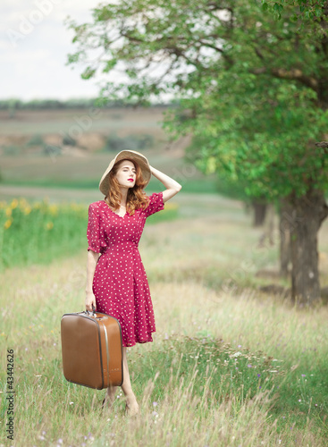 Photo: Redhead girl with suitcase at outdoor. Redhead girl with suitcase at outdoor.