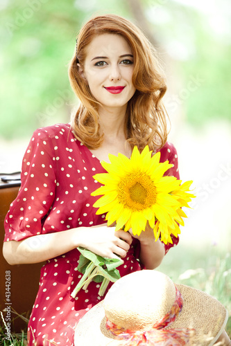 Foto: Redhead girl with sunflower at outdoor. Redhead girl with sunflower at outdoor.