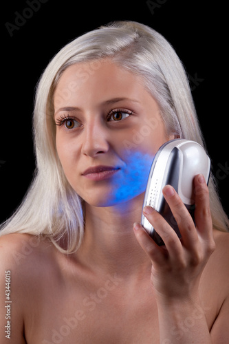 Photo: Young woman getting photo-therapy treatment with blue light Young woman getting photo-therapy treatment with blue light