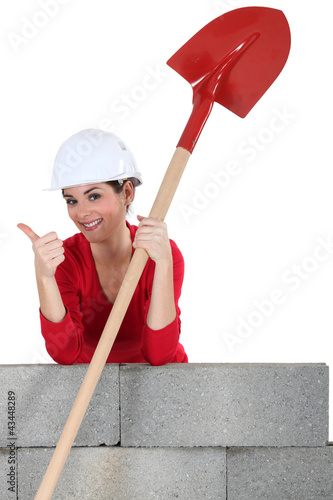 Photo: Female mason with shovel, giving the thumbs-up Female mason with shovel, giving the thumbs-up