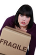 Woman carrying a heavy box marked fragile