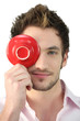 Young man holding a saucer in front of his eye