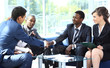 Two business man shaking hands with his team in