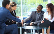 Two business man shaking hands with his team in office