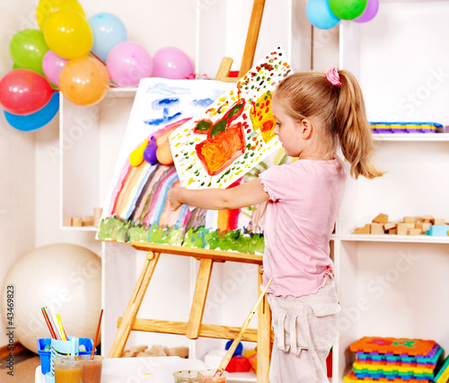 Photo: Child painting at easel. Child painting at easel.