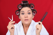 Woman with her hair in curlers holding scissors and a comb