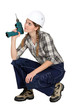 Handywoman crouching with drill