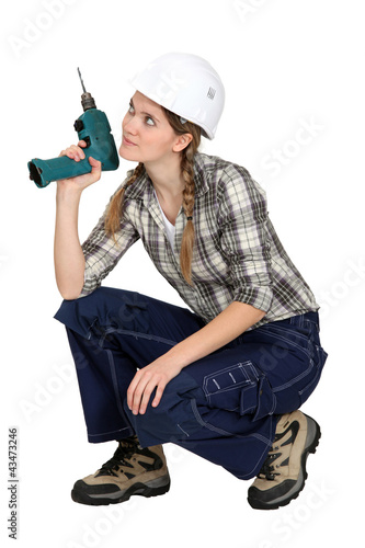 Photo: Handywoman crouching with drill Handywoman crouching with drill