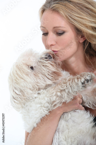 Foto: Middle-aged woman kissing dog. Middle-aged woman kissing dog.