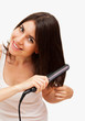 Foto: Smiling young woman straightening her hair Smiling young woman straightening her hair