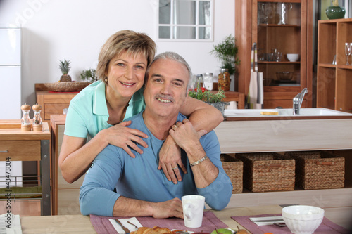 Photo: Middle-aged couple having breakfast together in kitchen Middle-aged couple having breakfast together in kitchen