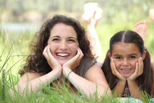 Photo: a woman and a little girl lying down in the grass a woman and a little girl lying down in the grass