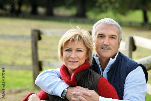 Photo: Couple hugging next to fence Couple hugging next to fence